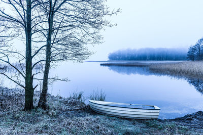 Boat lying beside still and misty lake