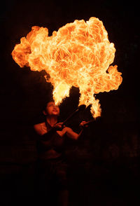 Close-up of man blowing fire against black background