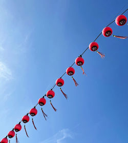 Low angle view of lanterns hanging against clear blue sky