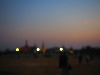 Defocused image of illuminated city against sky