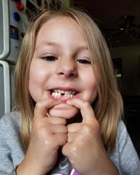 Close-up portrait of girl showing gap toothed at home