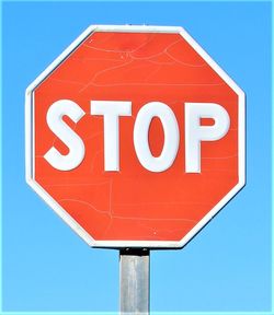 Low angle view of road sign against blue sky