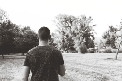 Rear view of man standing on field against clear sky