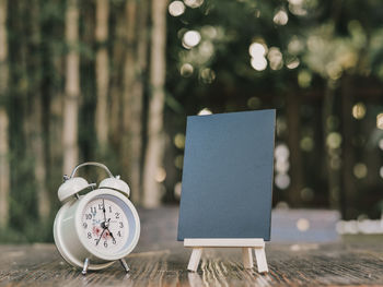 Close-up of clock and blank blackboard on table