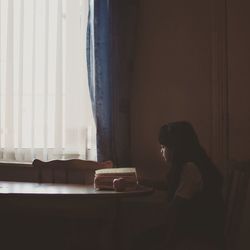 Girl reading book while sitting at home