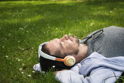 Man listening music while lying on field