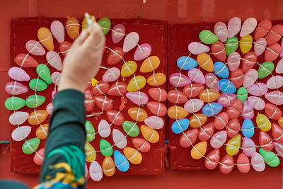 Cropped image of person throwing dart on colorful balloons