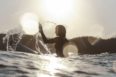 Female surfer in the ocean at sunset