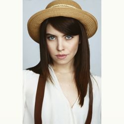 Portrait of beautiful young woman wearing hat against gray background