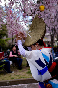 Low section of woman with cherry blossoms in park