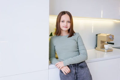 Portrait of young woman standing against wall