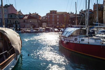 Sailboats moored on sea in city against sky