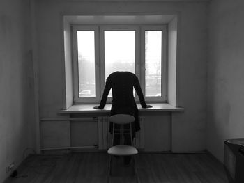 Man sitting on chair against window at home