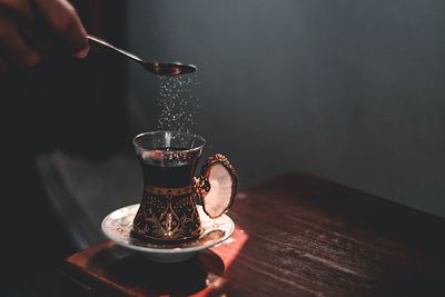 Close-up of hand pouring drink in glass on table