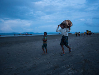 People walking on beach against sky