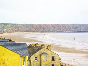 Houses by sea against clear sky