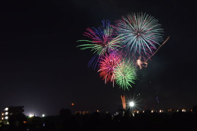 Low angle view of fireworks over buildings at night