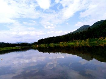 Scenic view of lake by mountains against sky