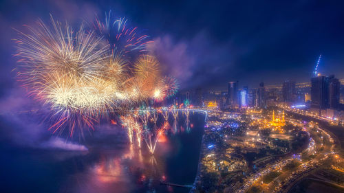 Firework display over illuminated buildings in city at night