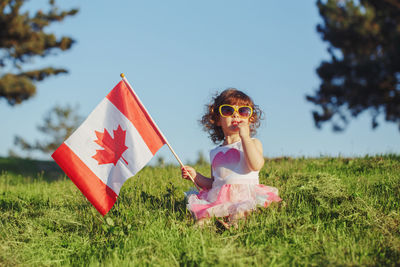 Full length of girl holding flag while standing on field