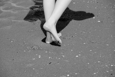 Low section of woman walking on sand