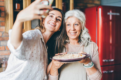 Portrait of smiling young woman having food at home