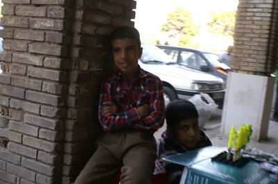 Portrait of young man standing against brick wall