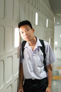 Portrait of young man standing by window