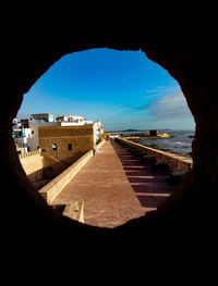 Buildings by sea against clear blue sky