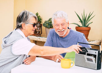 Smiling senior couple using radio on table