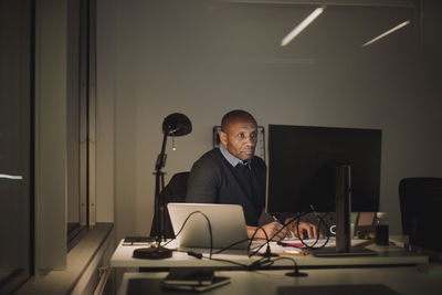 Dedicated businessman using computer while working overtime in office at night