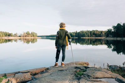 Rear view of man standing by lake against sky