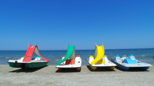 Deck chairs on beach against clear blue sky