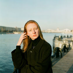 A woman stands at sunset near the bridge