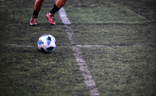 Low section of man playing with soccer ball on field