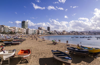 Boats at beach against sky in city