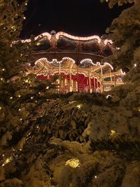 Illuminated carousel in amusement park against sky at night