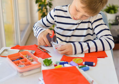 A caucasian boy  is learning to sew with his hands  homemade gift for mom, the concept of zero waste