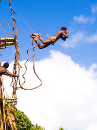 Low angle view of man jumping against blue sky