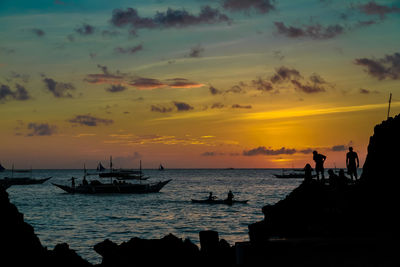 Silhouette people on boat in sea against sky during sunset