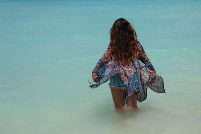 Rear view of woman standing in sea