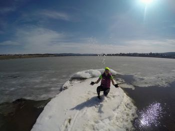 Rear view of man on shore against sky during winter