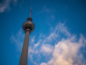 Low angle view of communications tower against cloudy sky