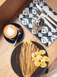 High angle view of coffee cup and pancake on table