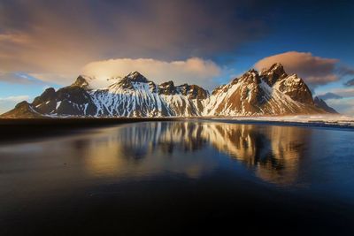 Scenic view of lake by snowcapped mountains against sky