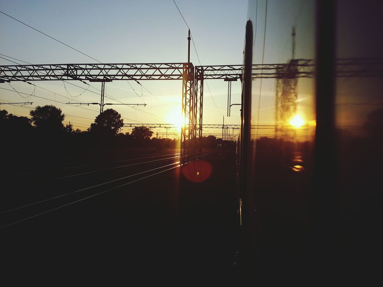 sunset, power line, electricity pylon, silhouette, electricity, sun, orange color, power supply, transportation, connection, cable, sky, clear sky, railroad track, fuel and power generation, built structure, rail transportation, technology, sunlight, no people