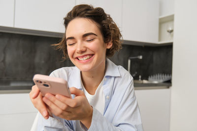 Portrait of young woman using mobile phone at home