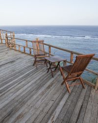 Empty chairs on beach against sky