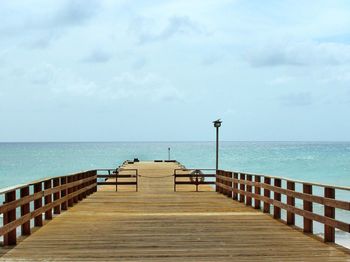 Pier on sea against cloudy sky