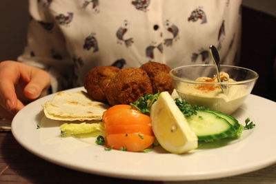 Mid section of woman sitting by plate full of snacks